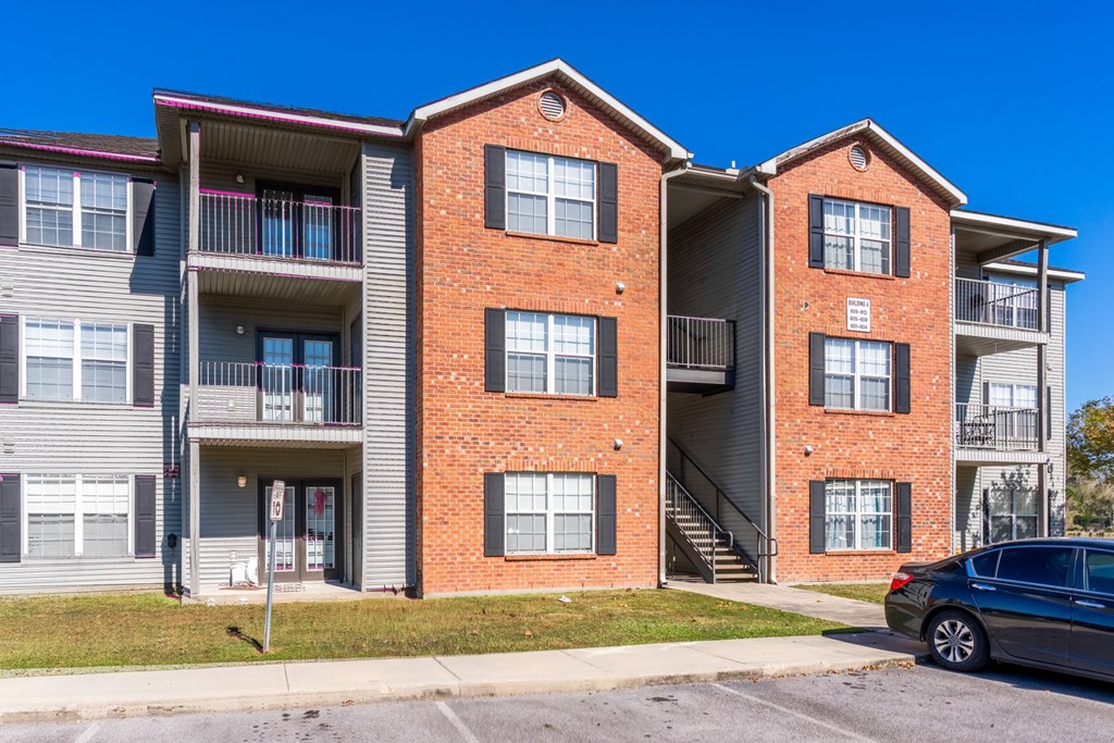A two-story apartment building with a car parked in front.