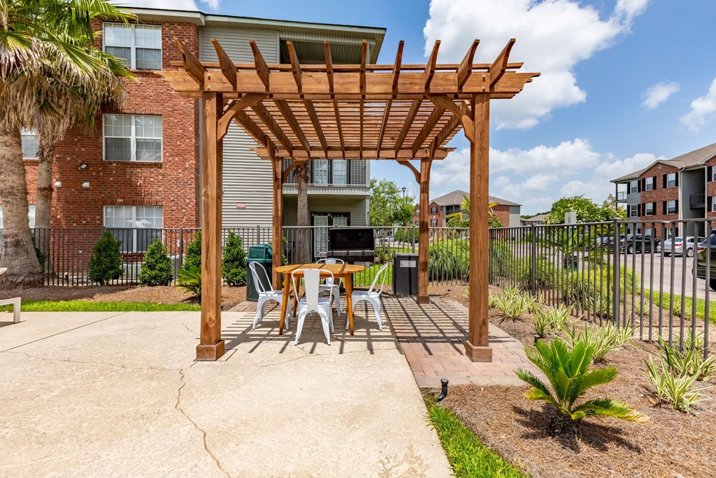 A wooden pergola is over a table set for four.