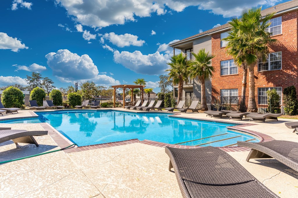 A large swimming pool surrounded by lounge chairs and palm trees.