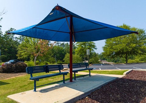two benches with an umbrella on a sidewalk