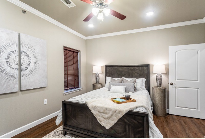 A bedroom with a large bed and a ceiling fan.