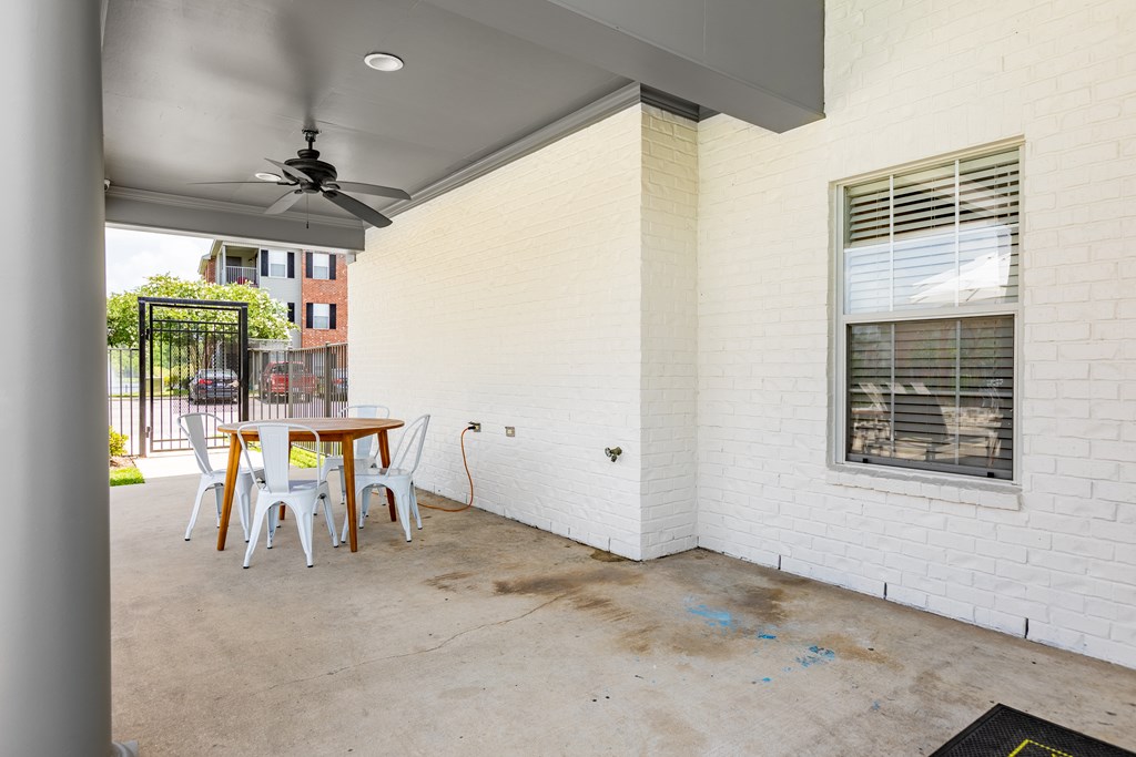 A patio with a table and chairs is covered by a roof.