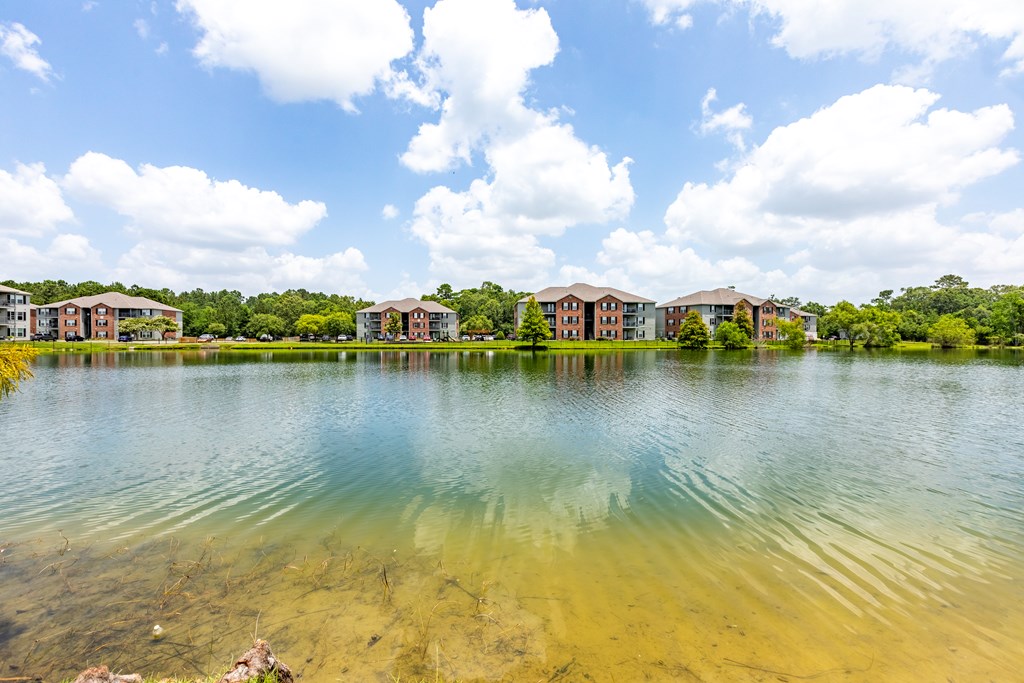 A serene lake with buildings in the background under a clear sky.