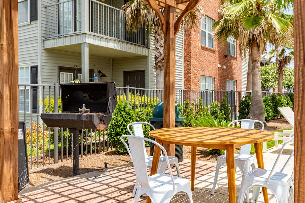 A patio with a table, chairs, and a grill.