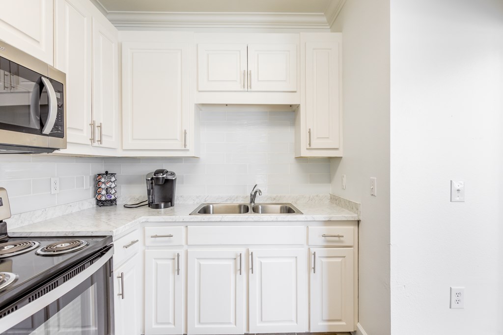 A kitchen with white cabinets and a black stove top.