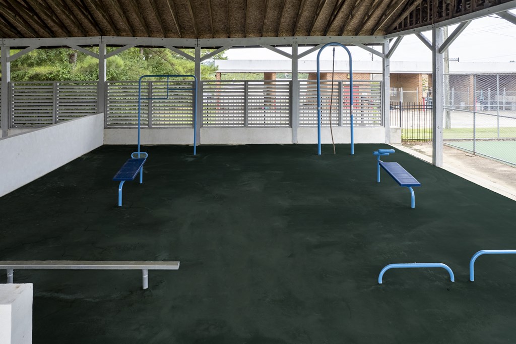an open area with benches and a tennis court in the background