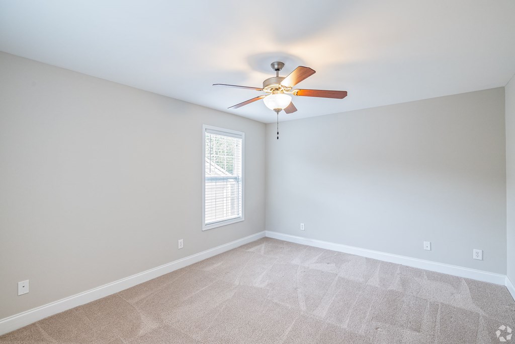 A room with a ceiling fan and a window.