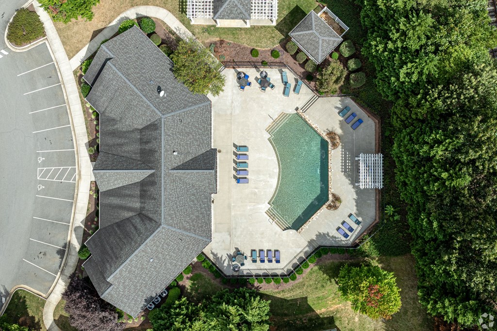 A bird's eye view of a residential area with a swimming pool and a parking lot.