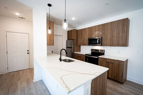 A modern kitchen with a white countertop and wooden cabinets.