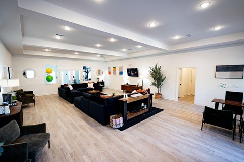 A living room with a black couch and a wooden floor.