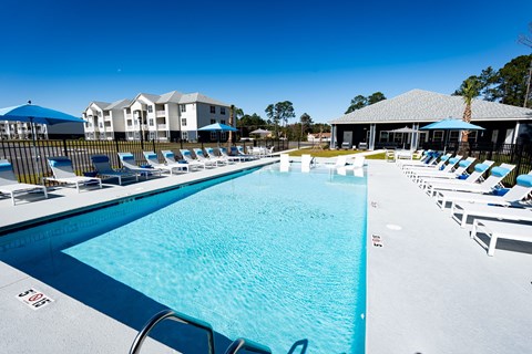A large swimming pool with lounge chairs and umbrellas.