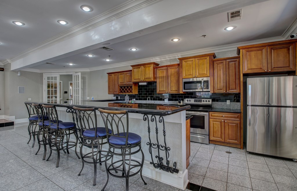 A kitchen with wooden cabinets and a bar area with blue stools.