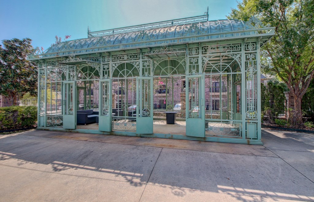 A green metal structure with a glass roof and arched windows.