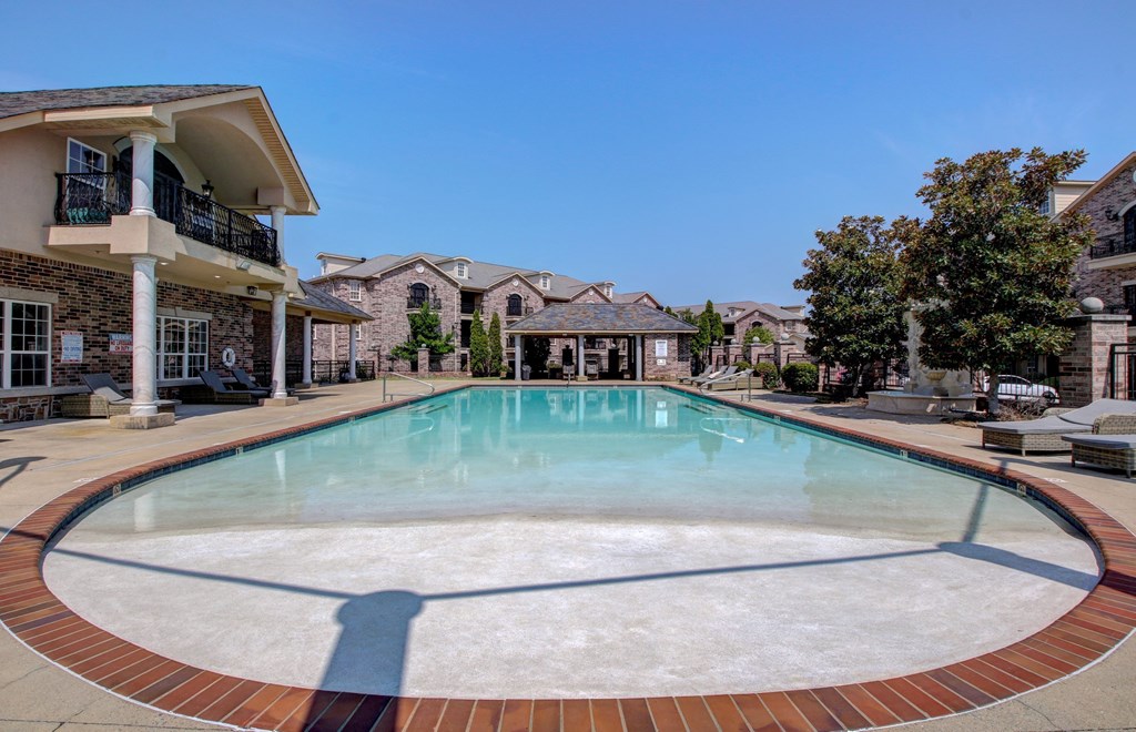 A swimming pool surrounded by a brick border in a residential area.
