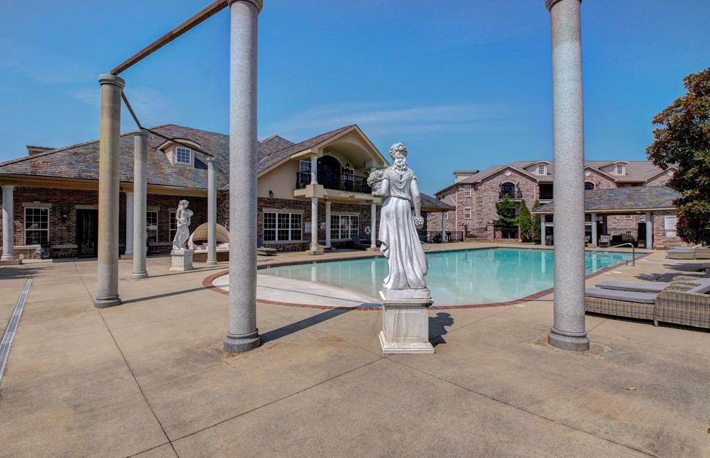 A statue of a woman stands in the middle of a pool surrounded by pillars.