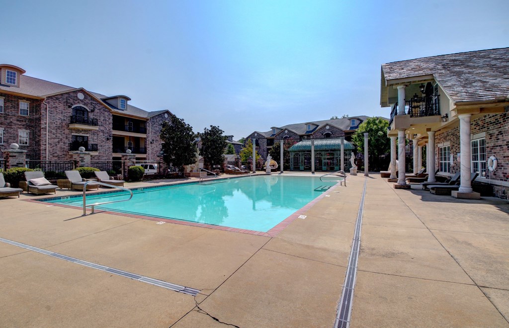A large swimming pool in front of a building with a sunny day.