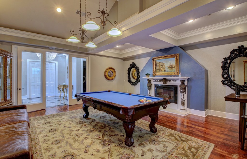 A pool table is in the middle of a room with a fireplace and a mirror.