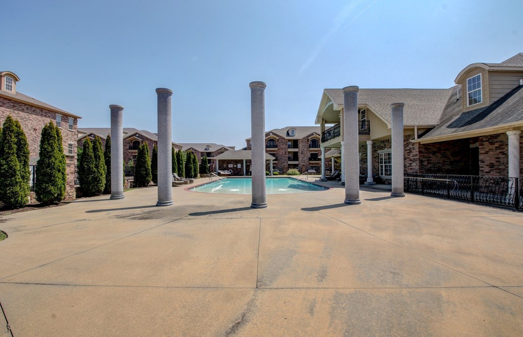 A large open courtyard with a pool and pillars.