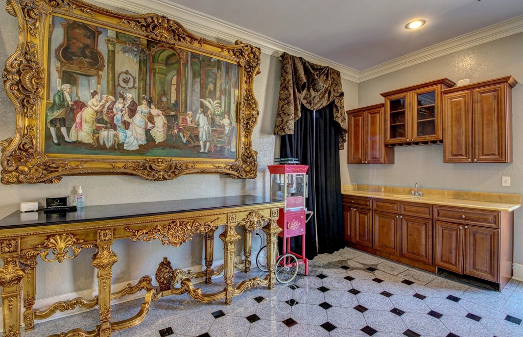 A large painting hangs above a black and white checkered floor in a room with a gold console table.