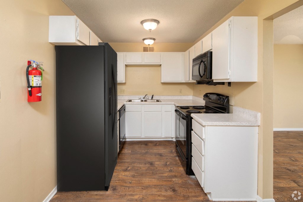 a kitchen with white cabinets and black appliances