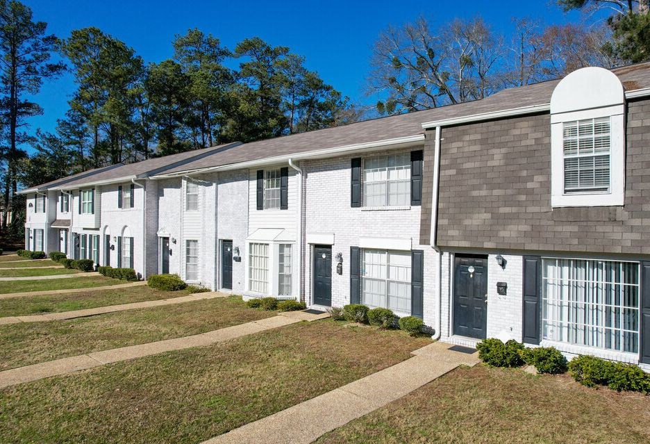 a row of white houses with black doors and a sidewalk