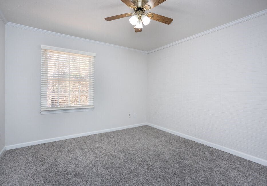 an empty bedroom with a ceiling fan and a window