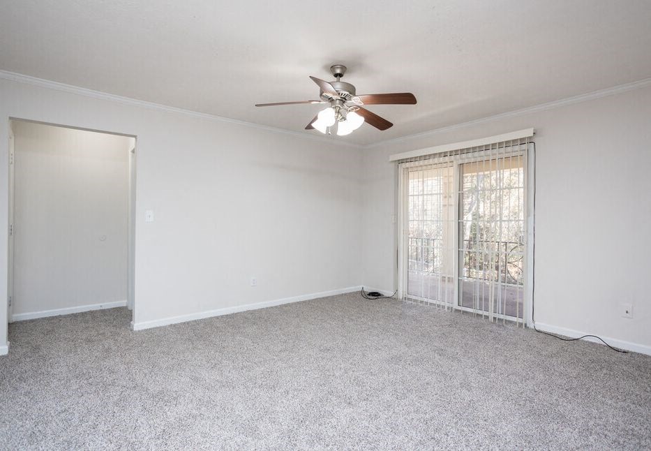 an empty living room with a ceiling fan and a window