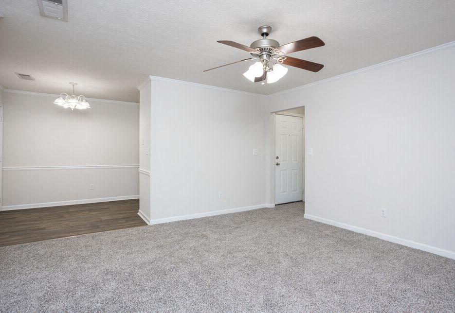an empty living room with a ceiling fan