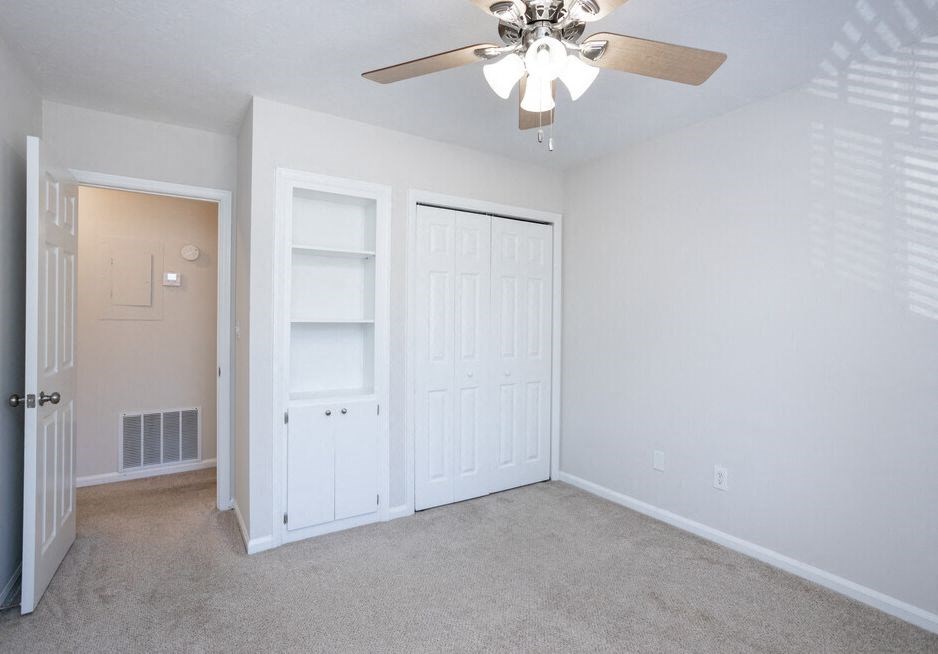 an empty bedroom with a ceiling fan and closet