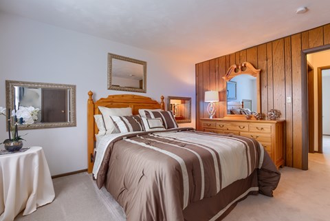 A bedroom with a large bed and a wooden headboard.