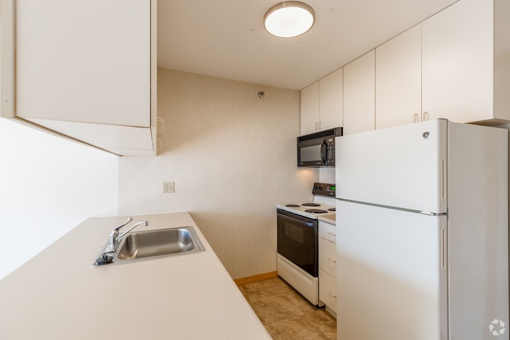 A kitchen with white appliances and a white counter.