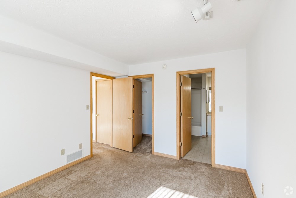 A room with a carpeted floor and two open doors.