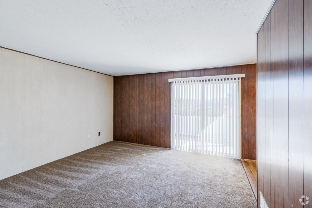 A room with a carpeted floor and a wooden door.