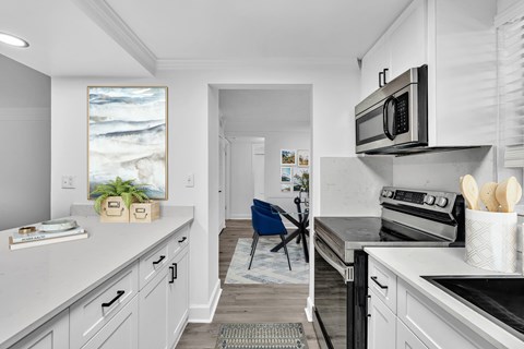 A kitchen with a white counter top and a blue chair.