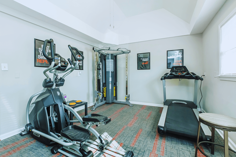 A home gym with a treadmill, elliptical trainer, and a stationary bike.