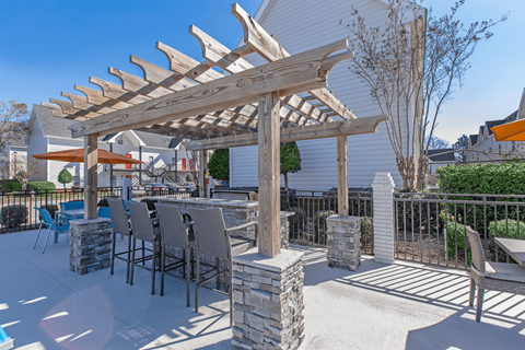 A wooden pergola is over a table with chairs.