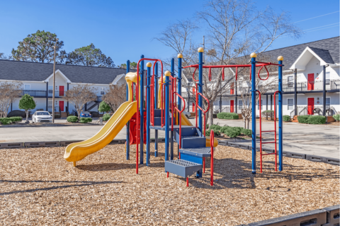 A playground with a yellow slide and a red and blue structure.