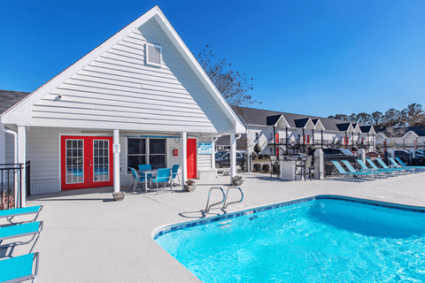 A pool in front of a white building with a red door.