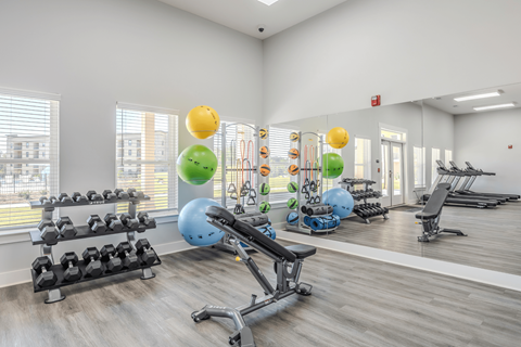 a gym with exercise equipment and weights on the floor and a large window