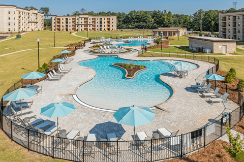 an aerial view of a large swimming pool with umbrellas and chairs around it