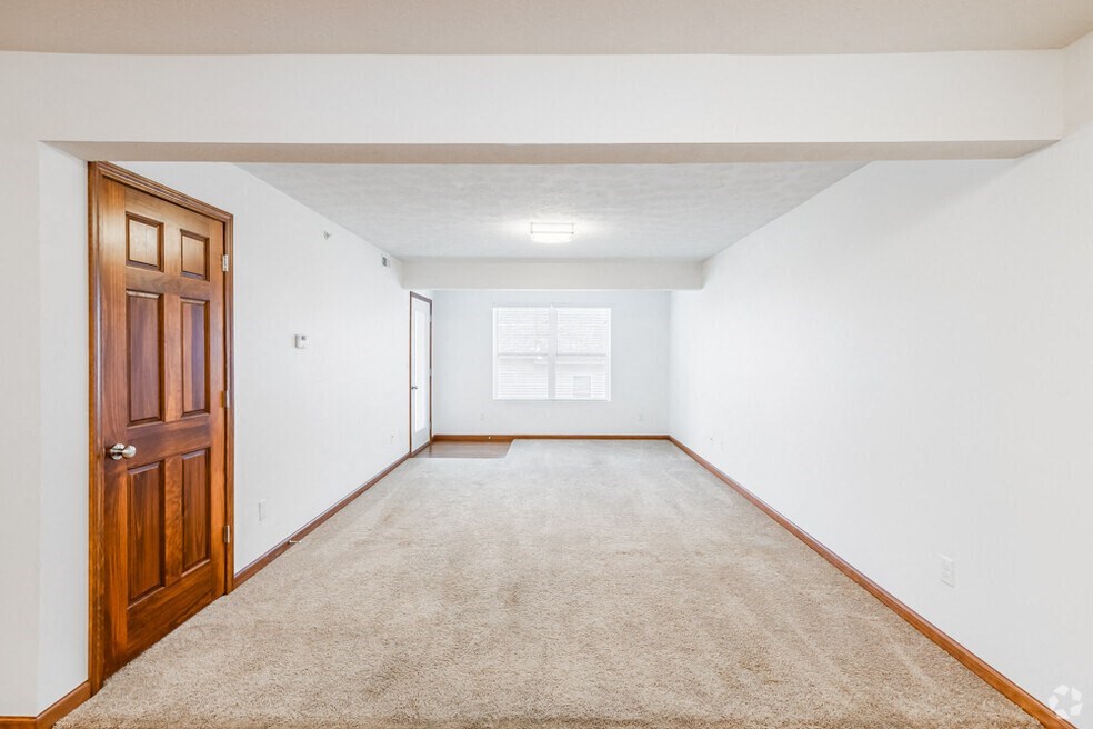 an empty living room with a wooden door and carpet