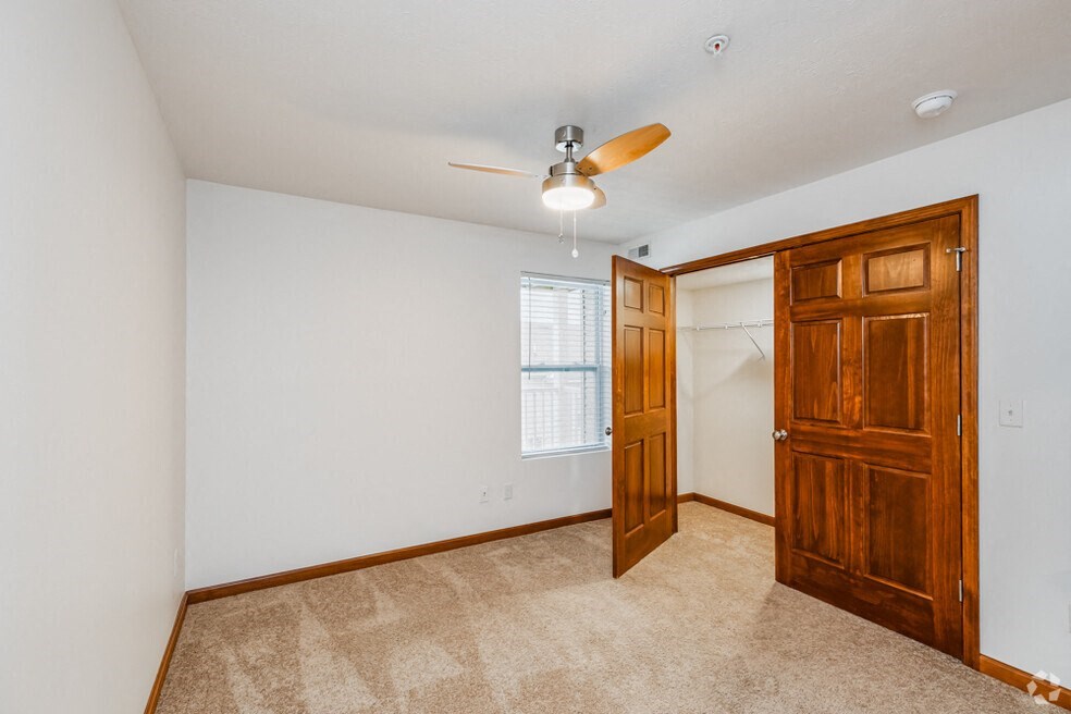 the living room is spacious and has a closet and a ceiling fan