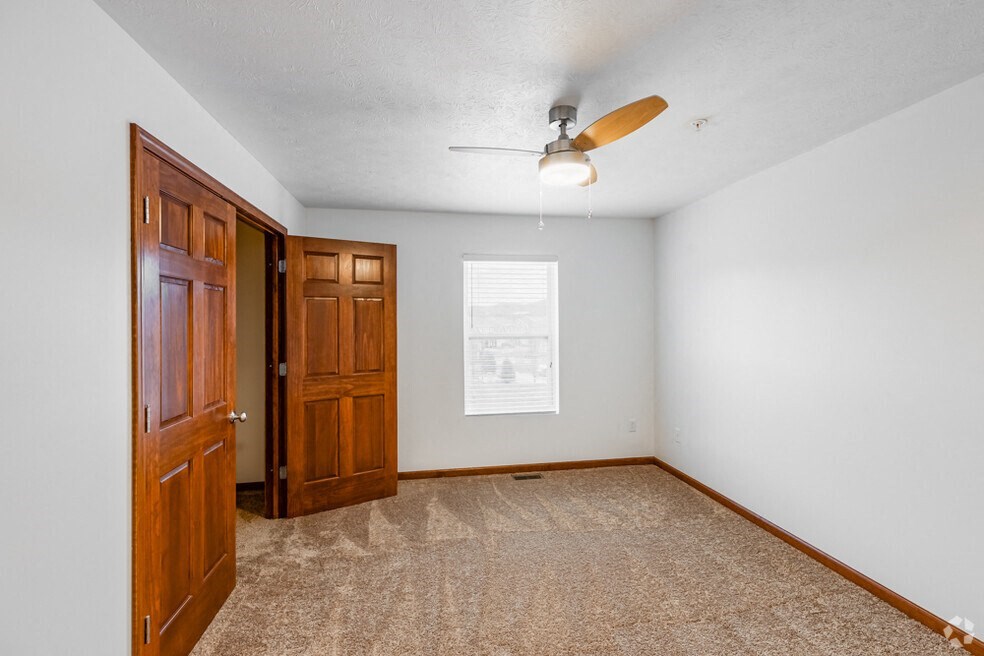 an empty room with a door and a ceiling fan