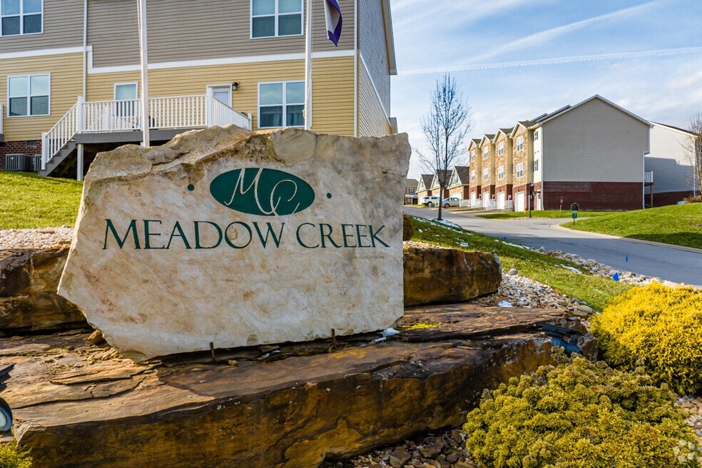 a stone sign that says in front of houses