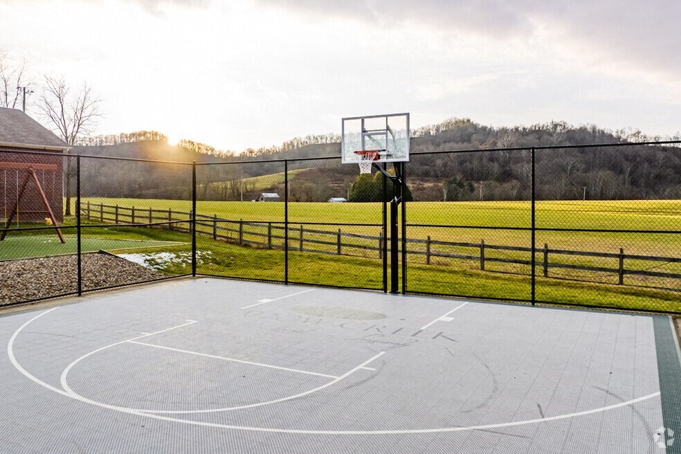 a basketball court with a view of a field and a fence