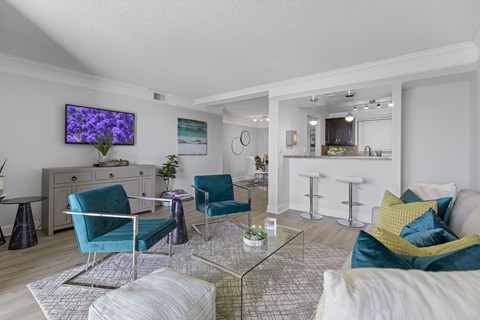 A living room with a glass coffee table and blue chairs.