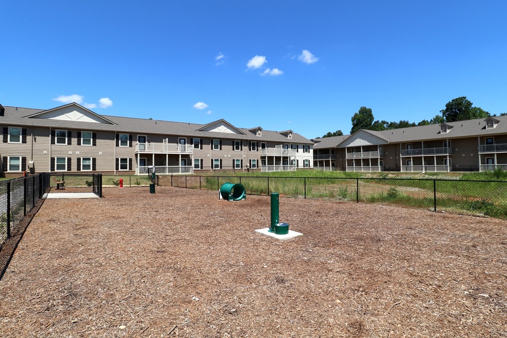A baseball field with a green base and a fence in the background.