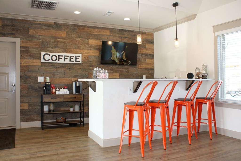A coffee bar with a brick wall and orange stools.