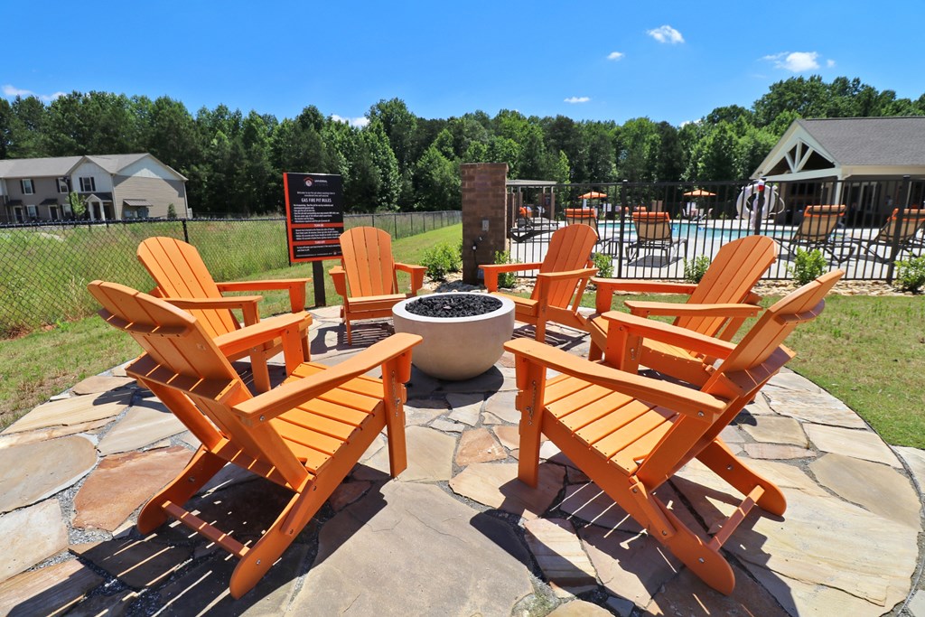 A fire pit surrounded by chairs in the middle of a stone circle.