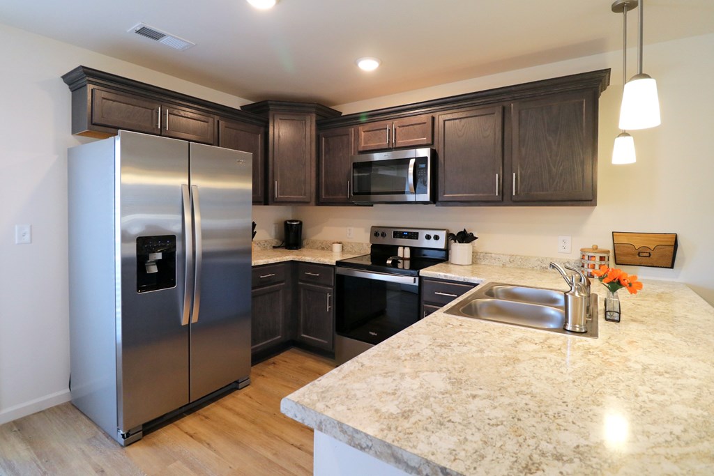 A kitchen with a granite counter top and stainless steel appliances.